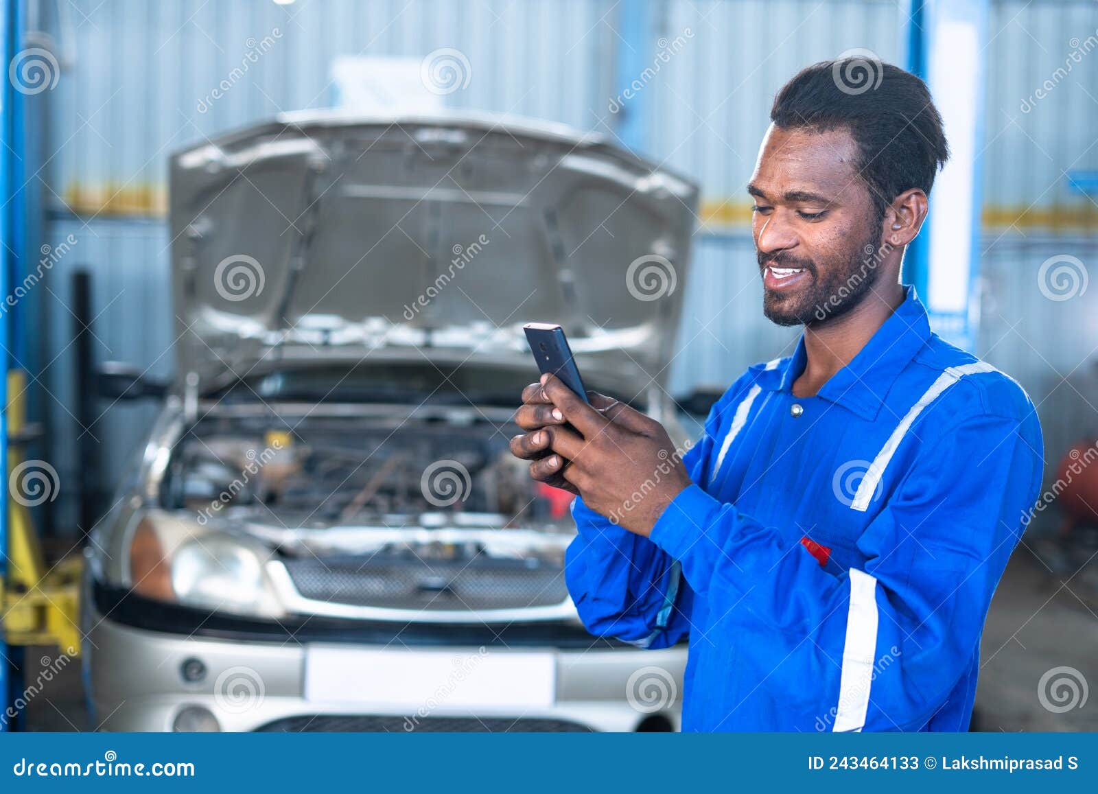 Happy Car Mechanic Busy Using Mobile Phone at Garage in Front of Repair Car  with Opened Hood - Concept of Using Stock Image - Image of engineer,  professional: 243464133