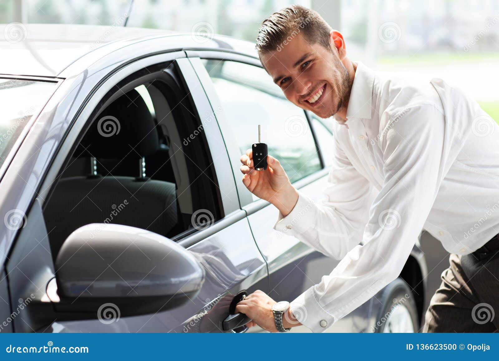 happy car owner is showing thumbs up and his new car key.