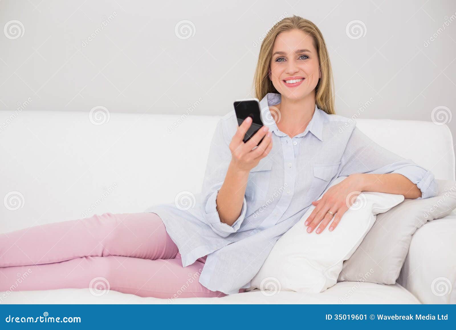 Happy Casual Blonde Relaxing on Couch Holding Smartphone Stock Image ...