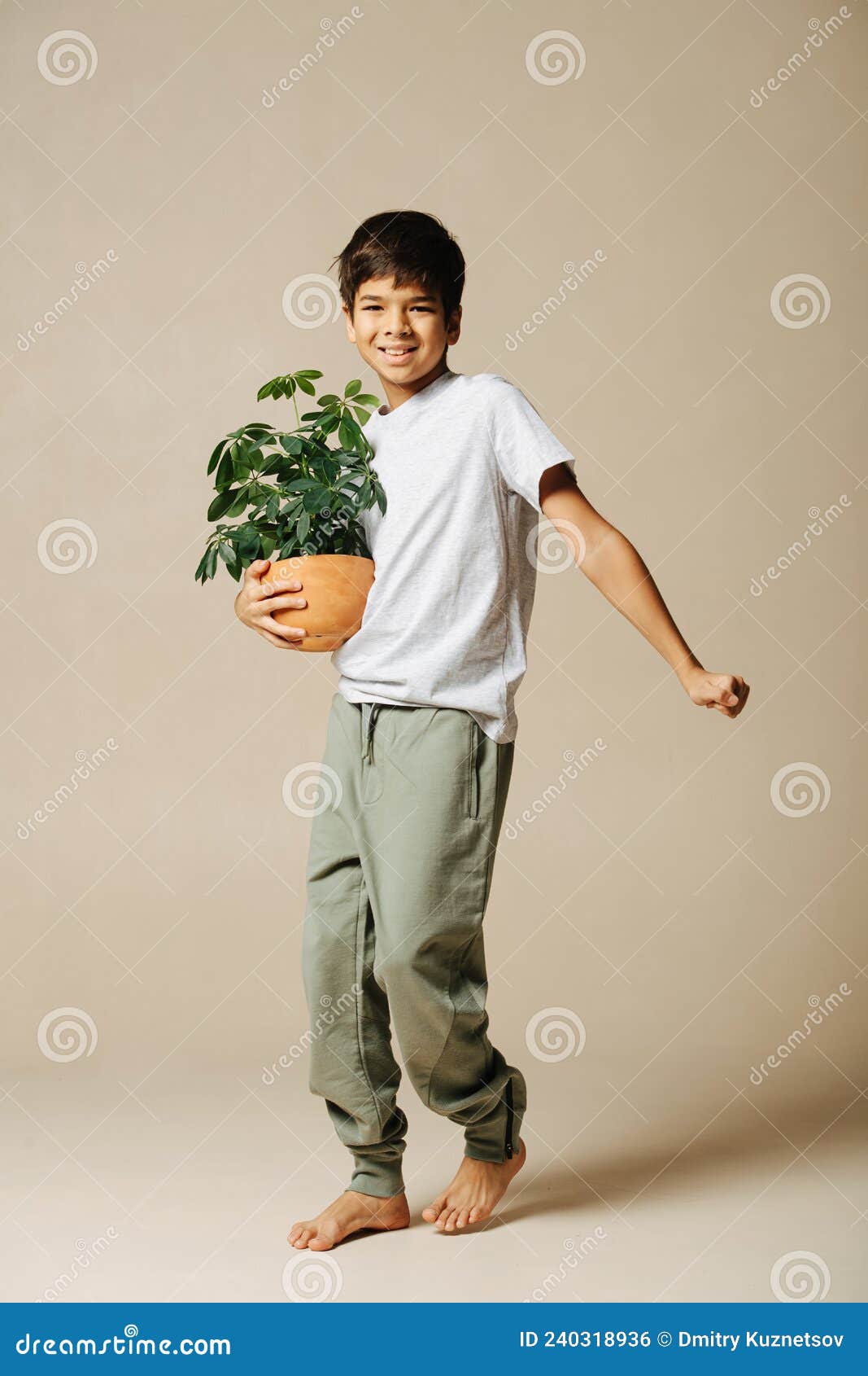 Happy Casually Dressed Indian Boy Holding a Potted Plant in His Arms