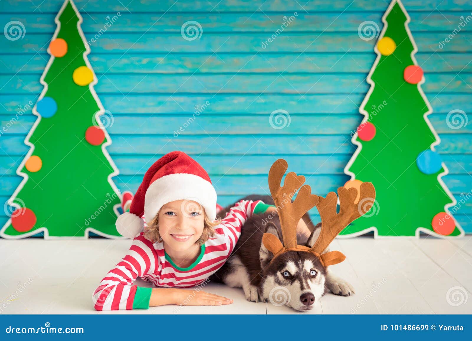 Happy child and dog on Christmas eve Kid and pet dressed in Santa Claus hat Girl having fun with husky at home Chinese calendar new year concept