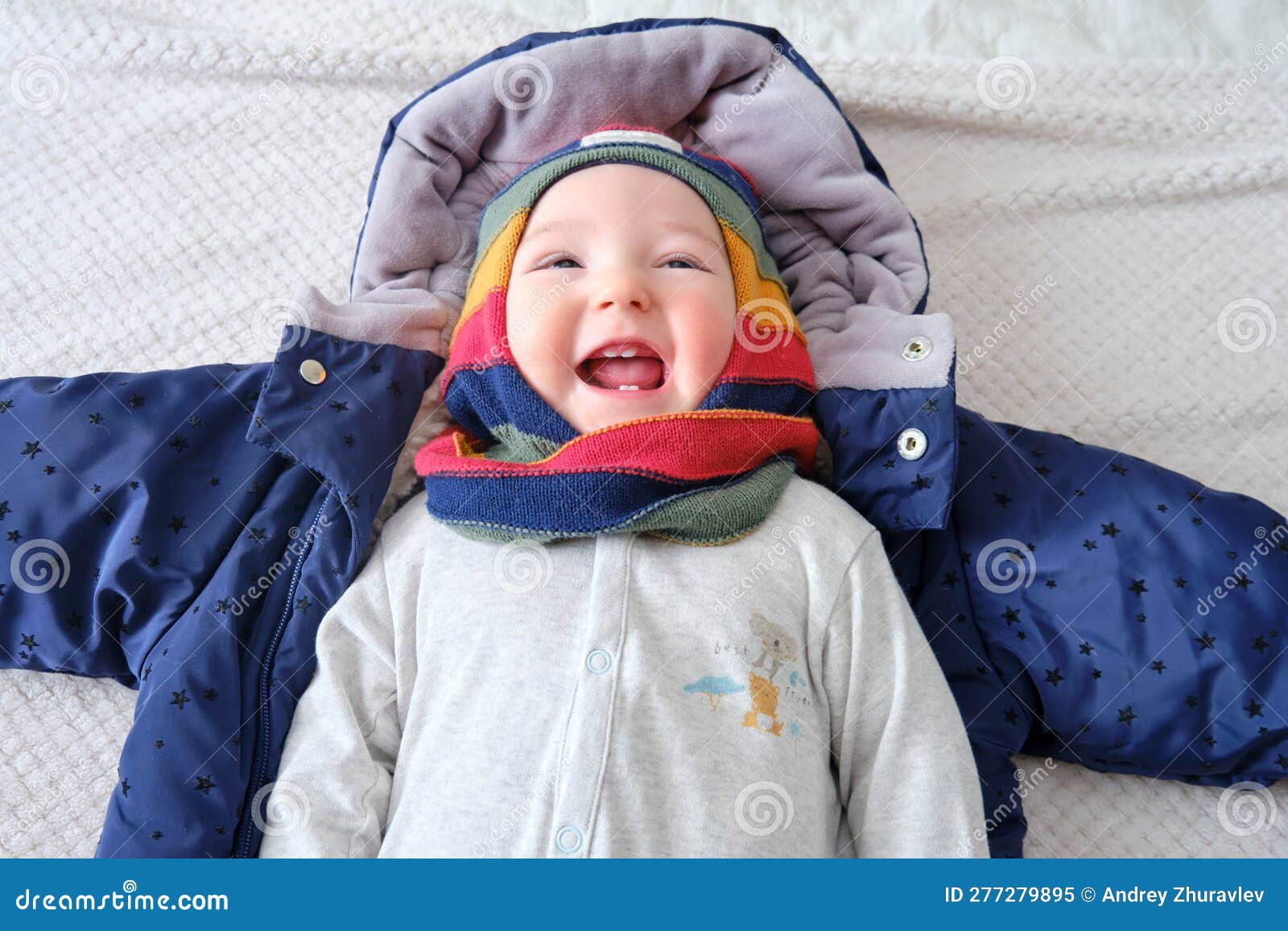 A Happy Child Dressed in Warm Winter Clothes is Lying on the Bed Stock