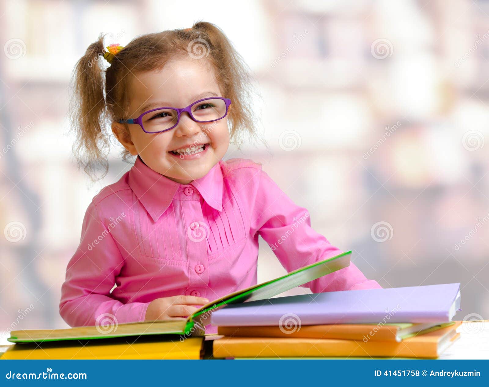 happy child girl in eyeglasses reading book