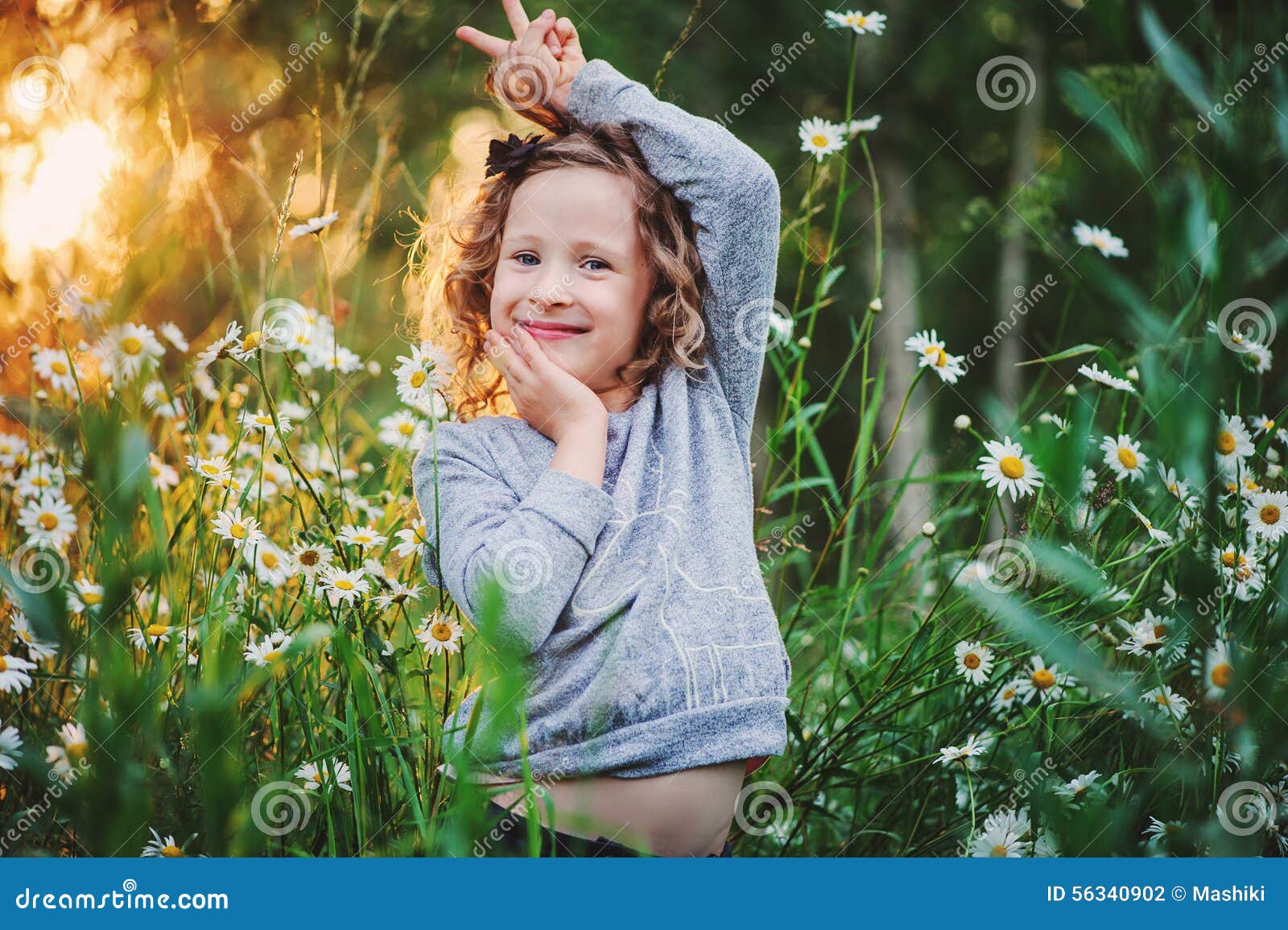 happy child girl fooling on summer field with flowers