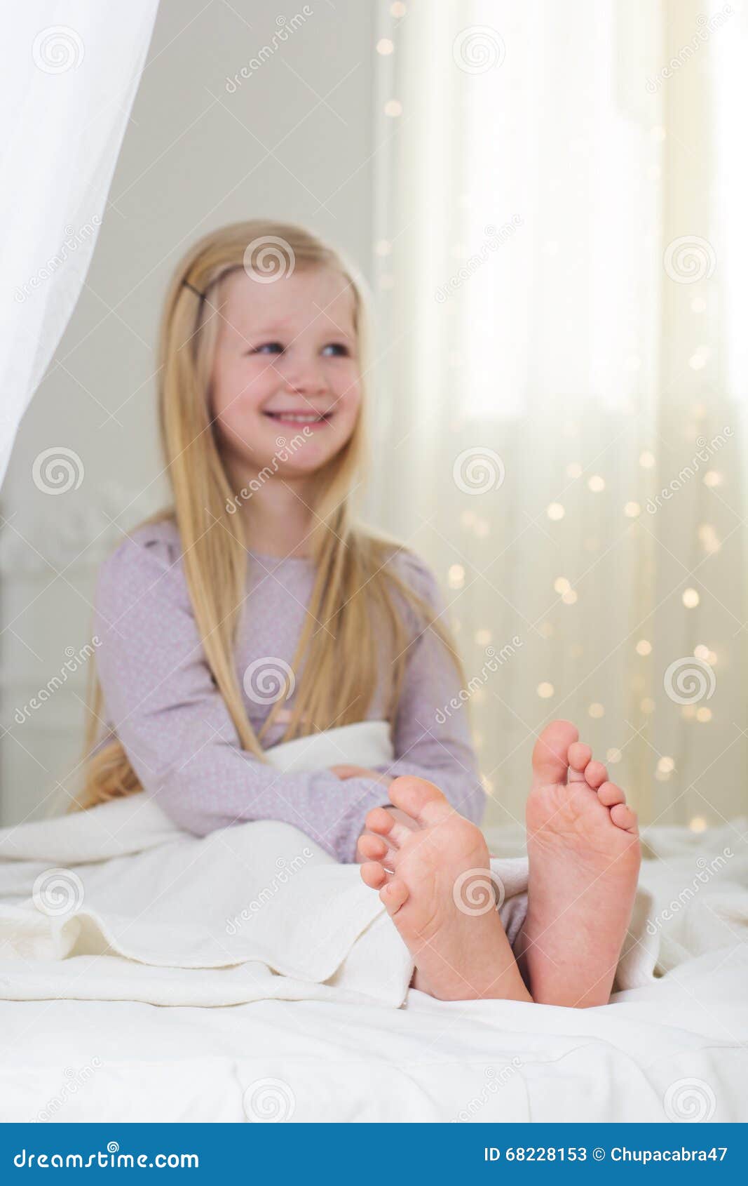 Portrait Of Happy Little Girl Sitting On Bed With Legs Crossed Kid