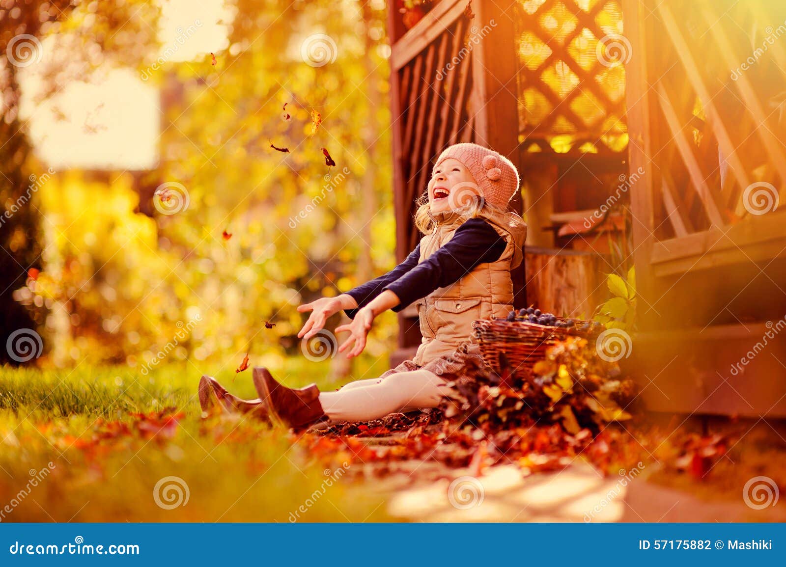 happy child girl throwing leaves on the walk in sunny autumn garden