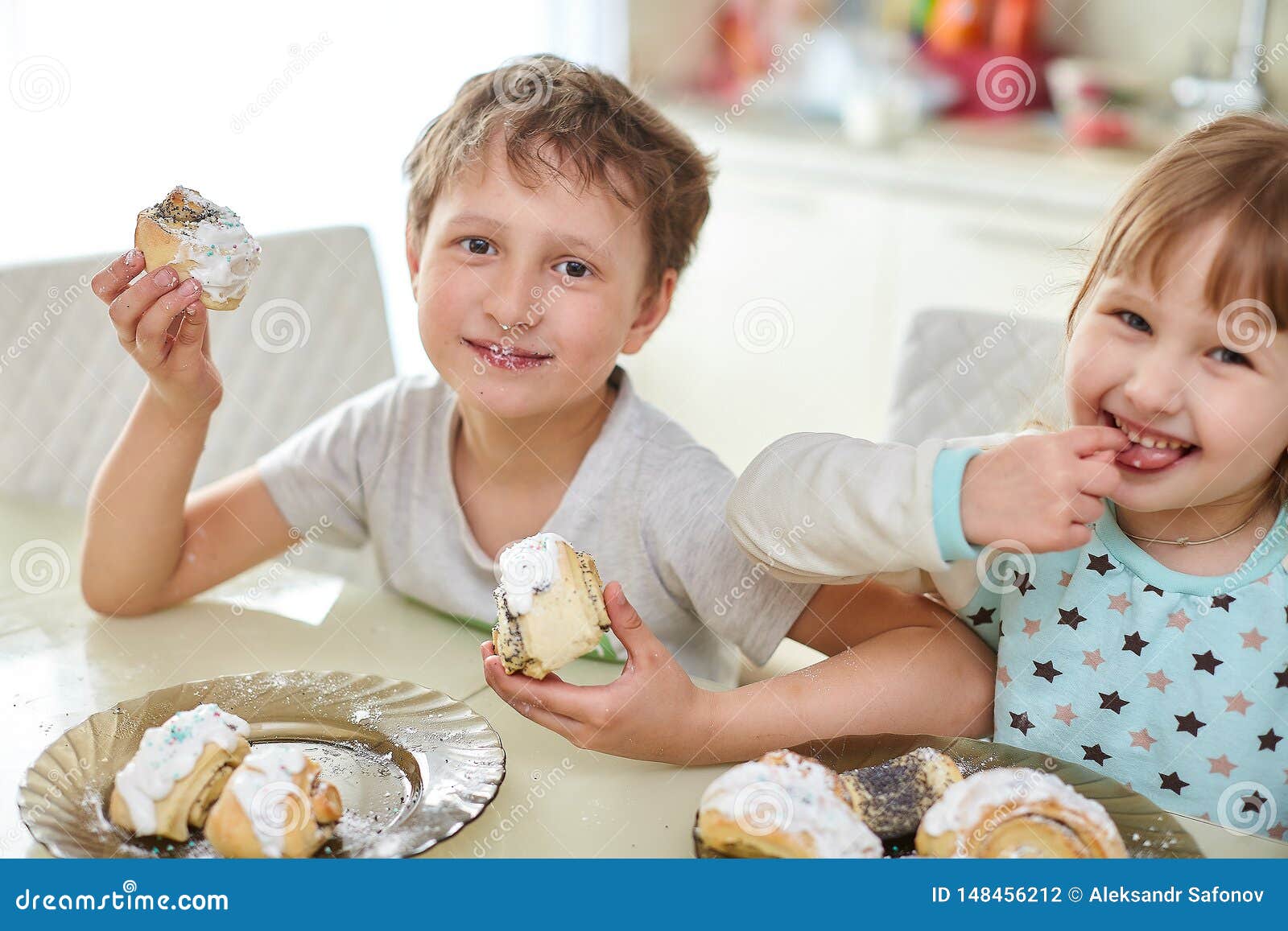 Happy Children Eat Pastries in the Bright Kitchen at the Table Stock