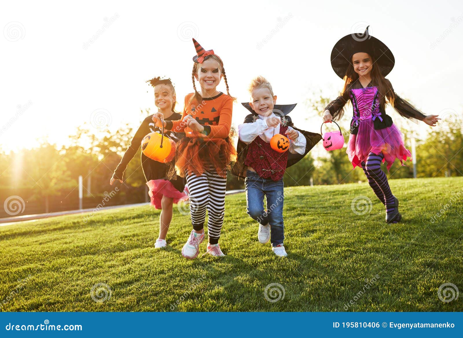 happy children in halloween costumes running on lawn