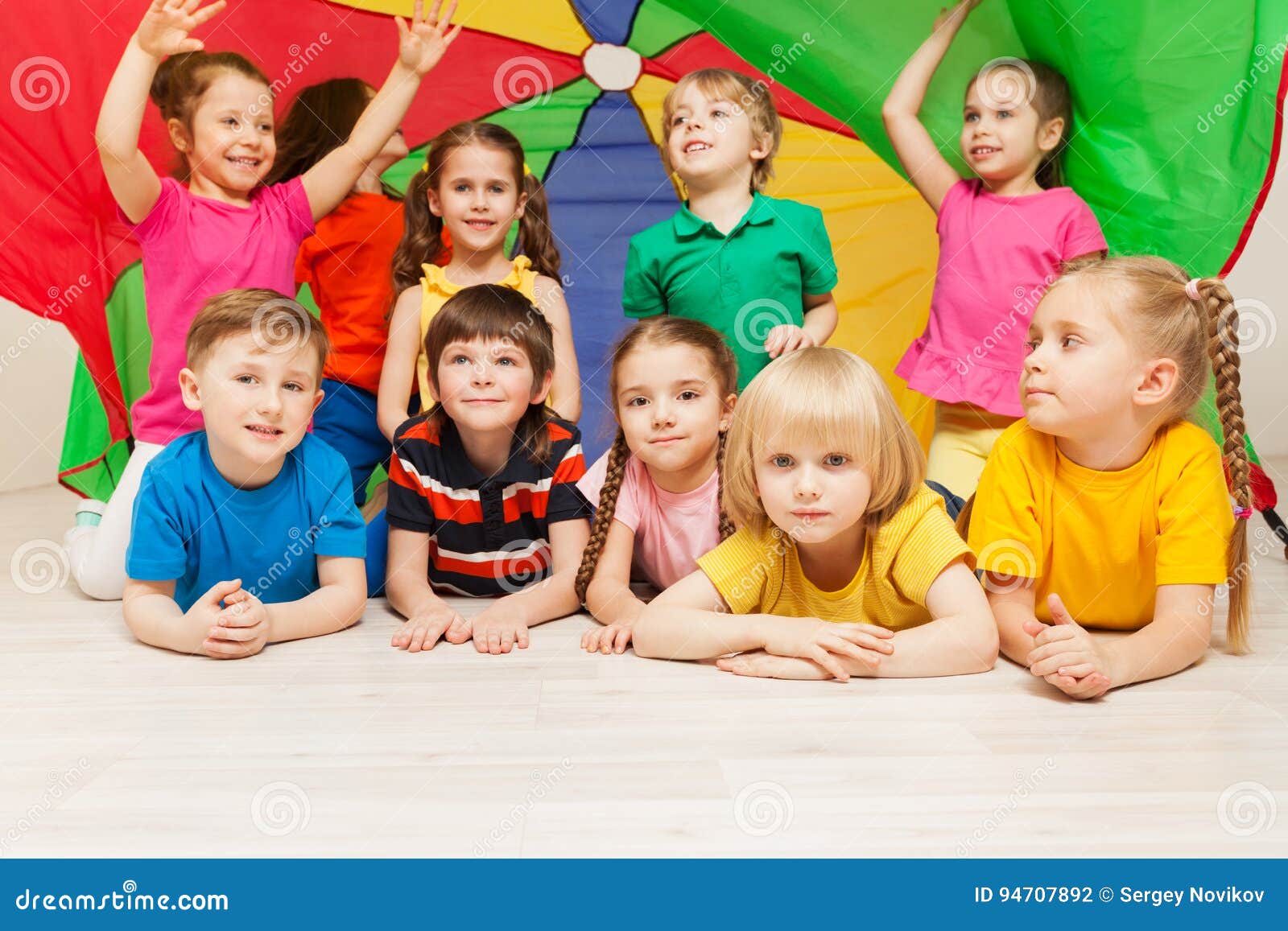 happy children hiding under tent made of parachute