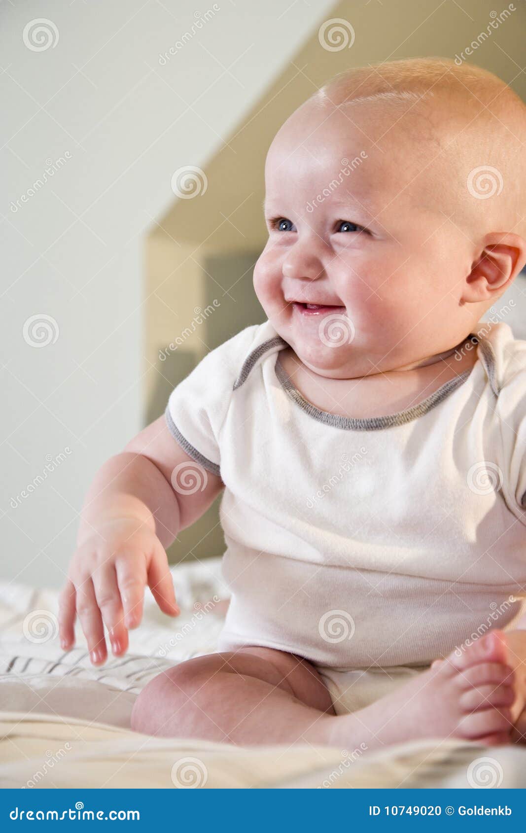 happy chubby baby sitting on bed