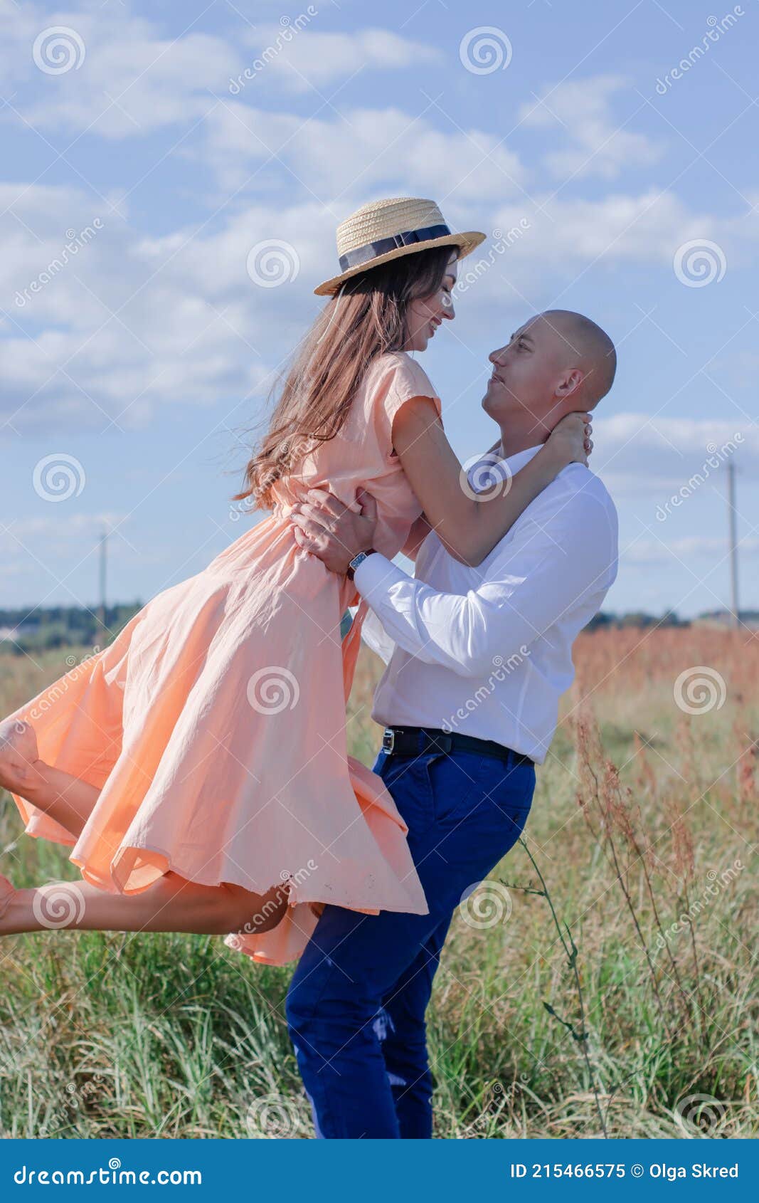 happy couple dancing field brunette cream dress bald men white shirt blue pants husband wife 215466575
