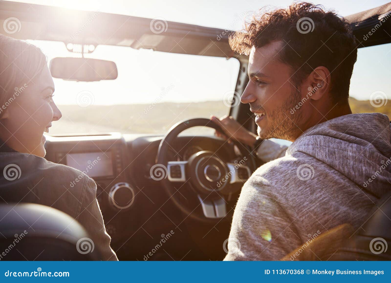 happy couple driving in car with sunroof open, passenger pov