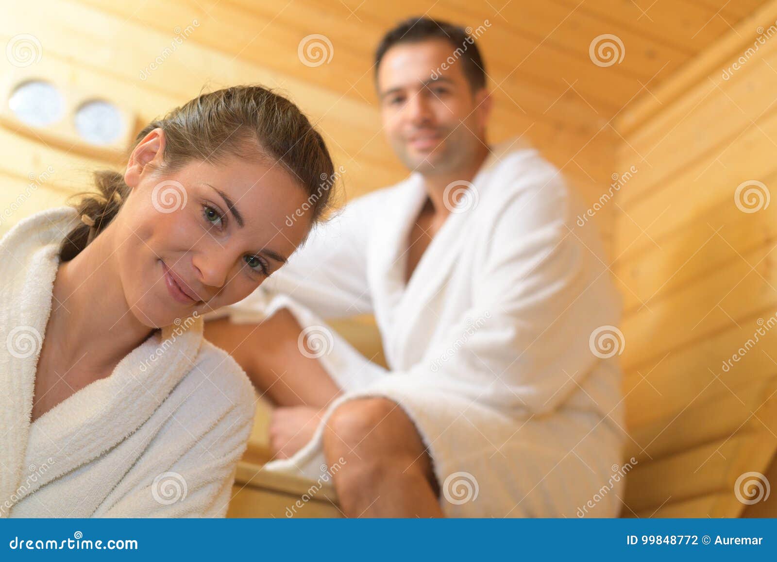 Man and woman in steam bath with towels smiling - Foto de stock