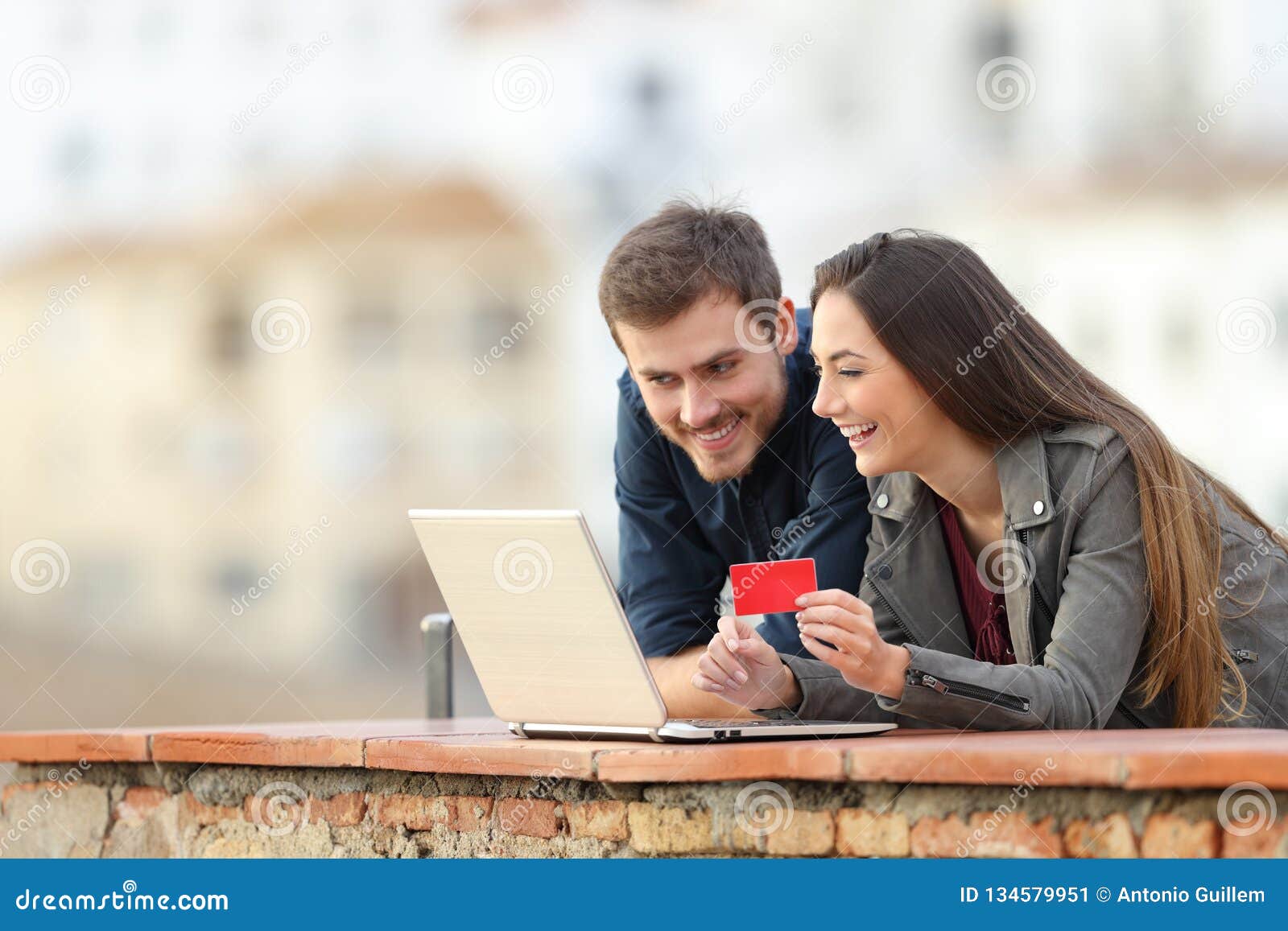 happy couple paying online with credit card and laptop