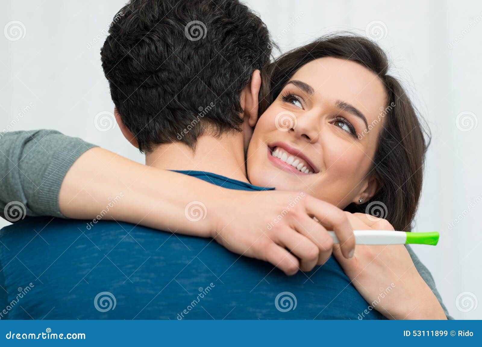 Happy couple with a pregnancy test. Closeup of happy young women embracing men after positive pregnancy test