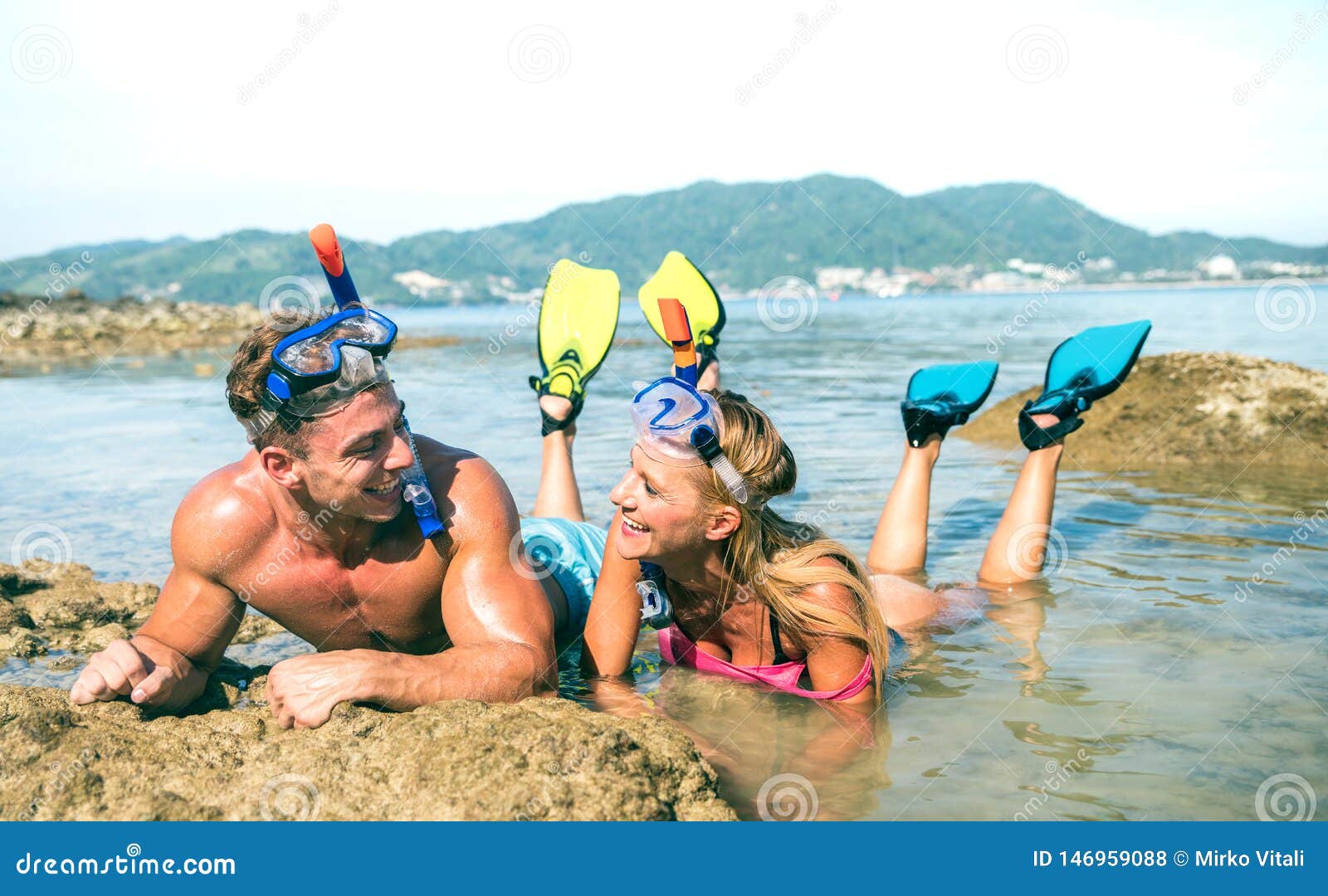 happy couple of vacationer in love having fun at water on tropical beach in thailand with snorkel mask and fins - active youth