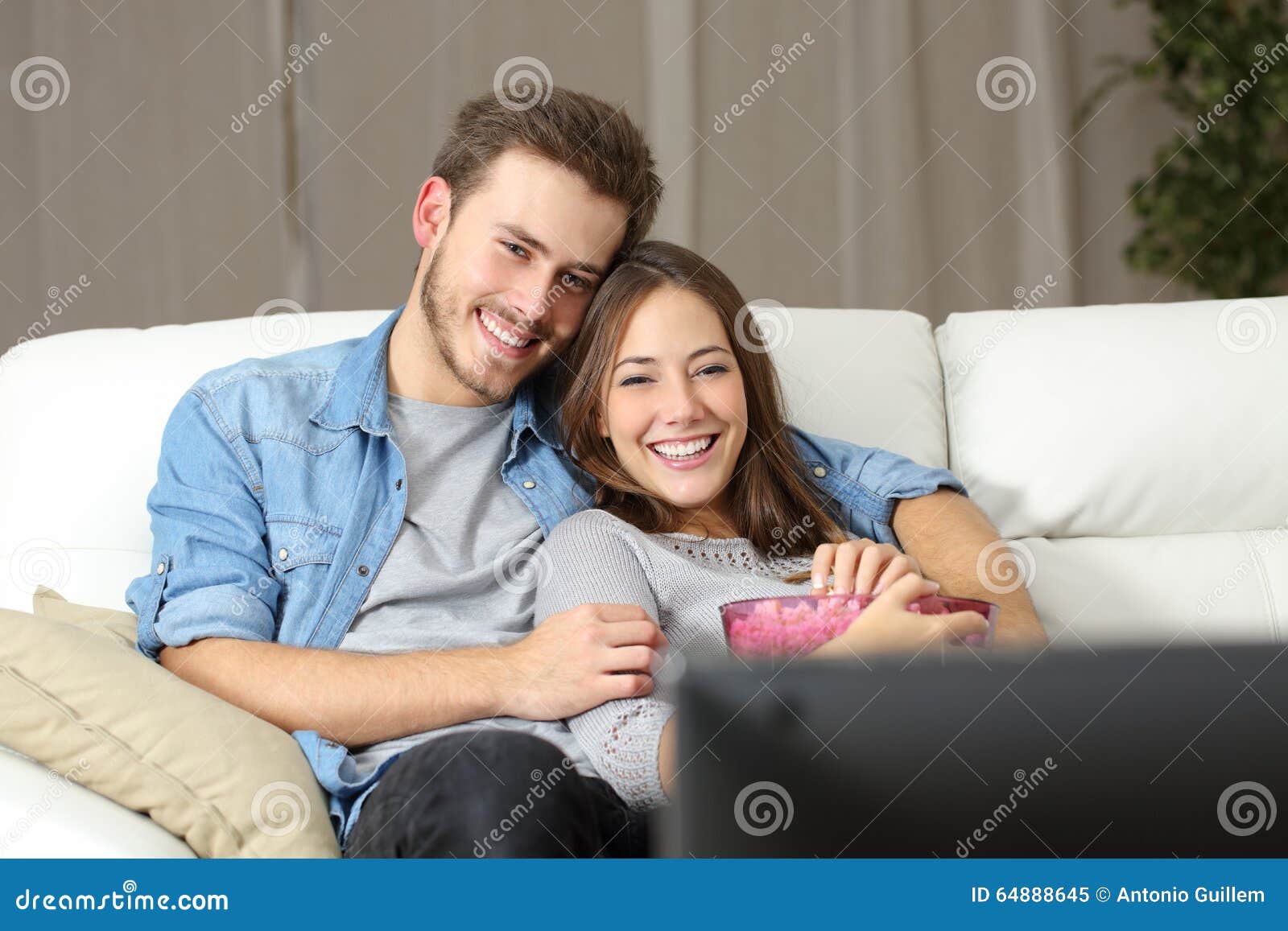 happy couple watching movie on tv