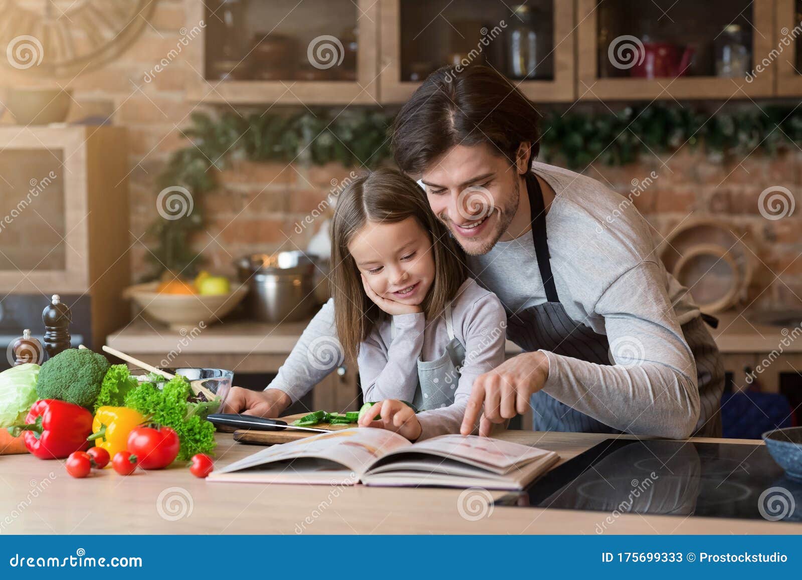 happy dad and little daughter checking recipe in cookbook together