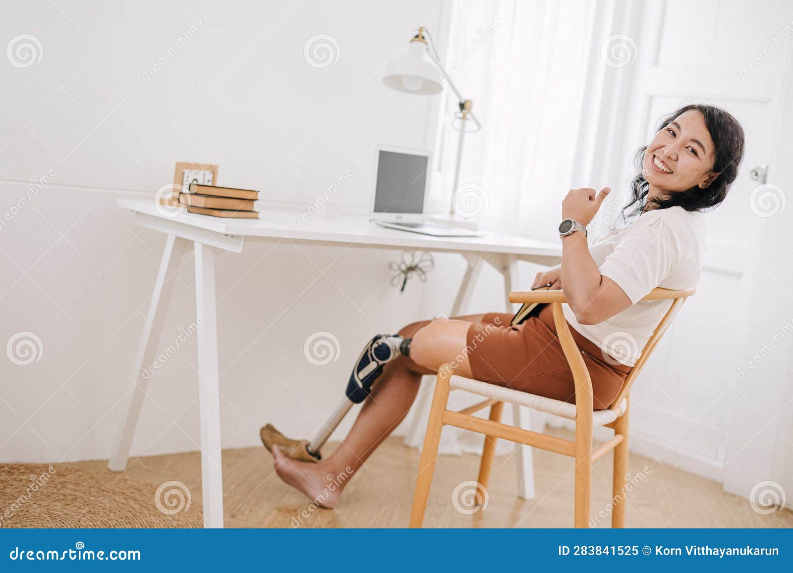 Smiling Young Woman With Prosthetic Leg Using Laptop In Living