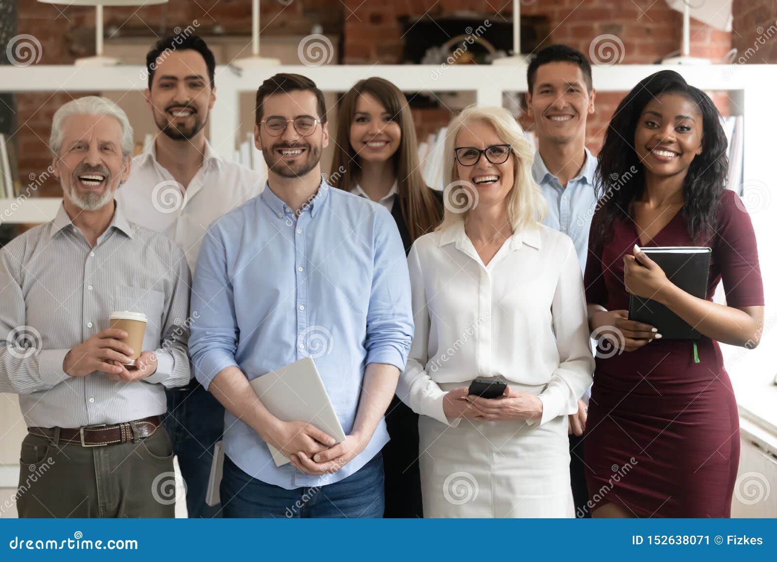 happy diverse business team standing in office looking at camera
