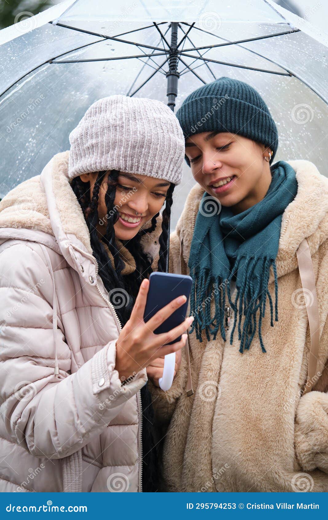 Happy Dominican Lesbian Couple Using The Phone In A Rainy Day Of Winter 