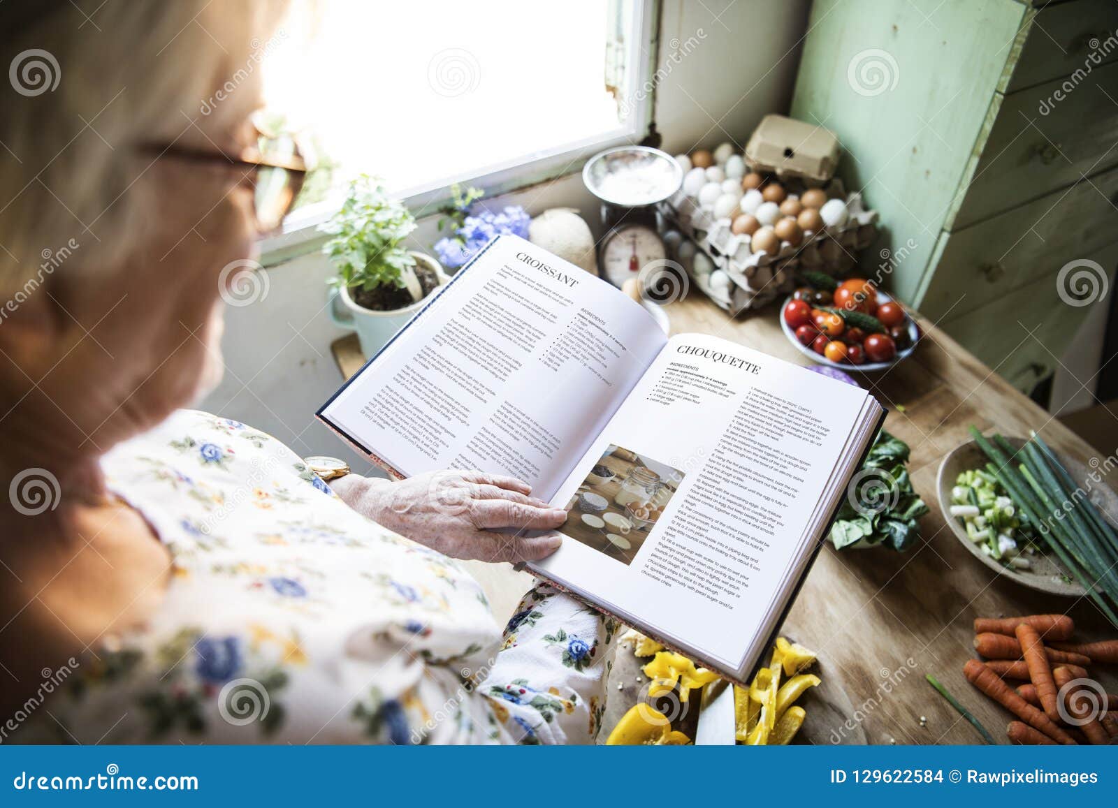 happy elderly woman reading a cookbook