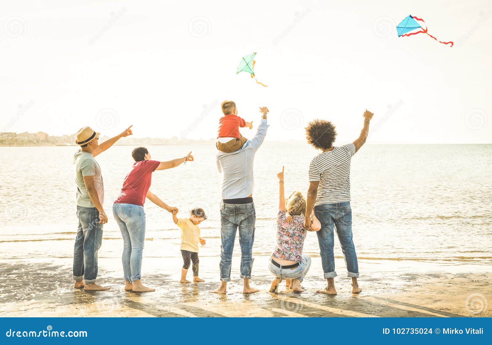 happy families group with parents and children playing with kite at beach