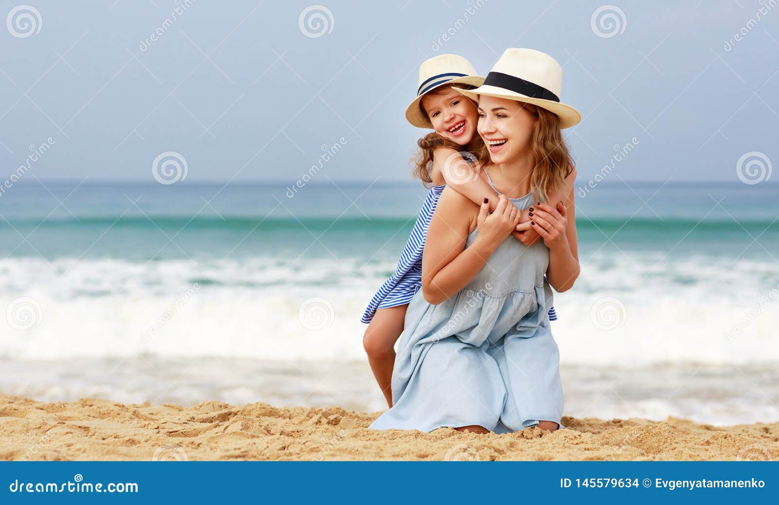 happy family at beach. mother and child daughter hug at sea