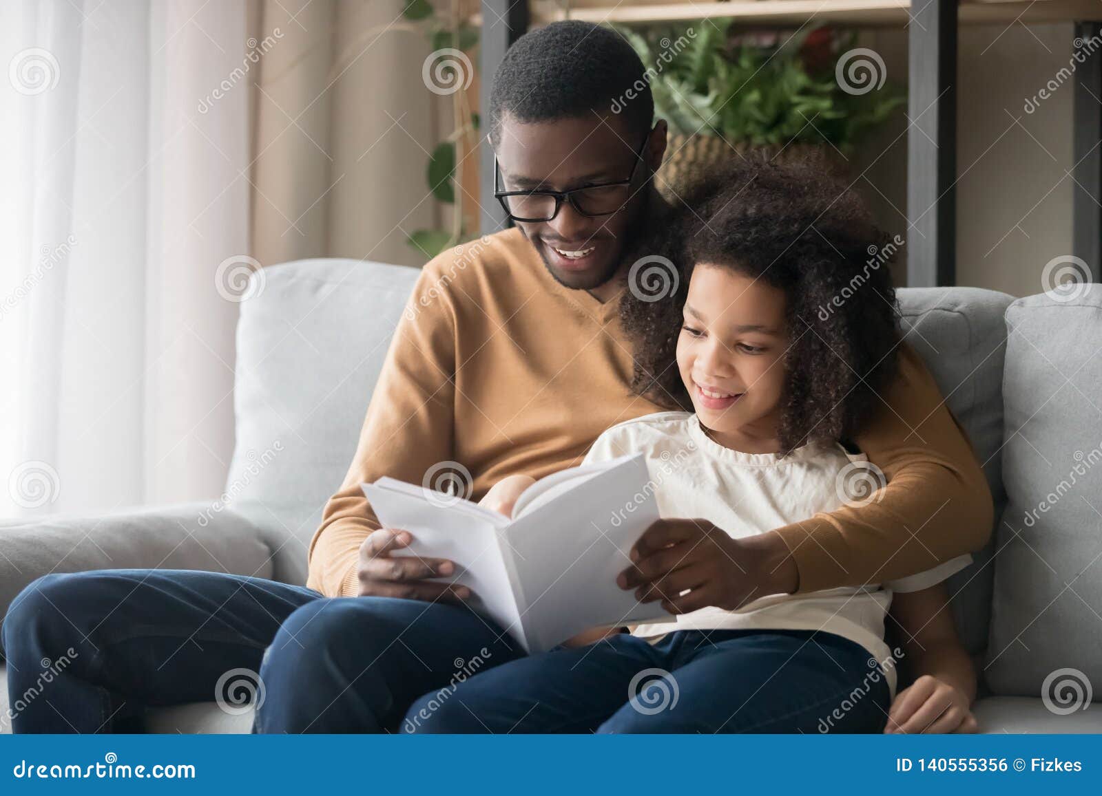 happy family black father and kid daughter reading story book