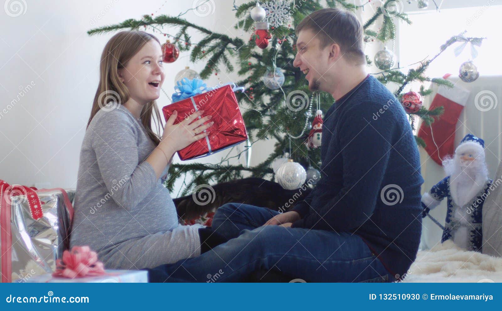 Happy Young Pretty Couple Sit Near Beautiful Decorated Christmas Tree Happy Young Pretty Couple Sit Near Beautiful Decorated Christmas Tree