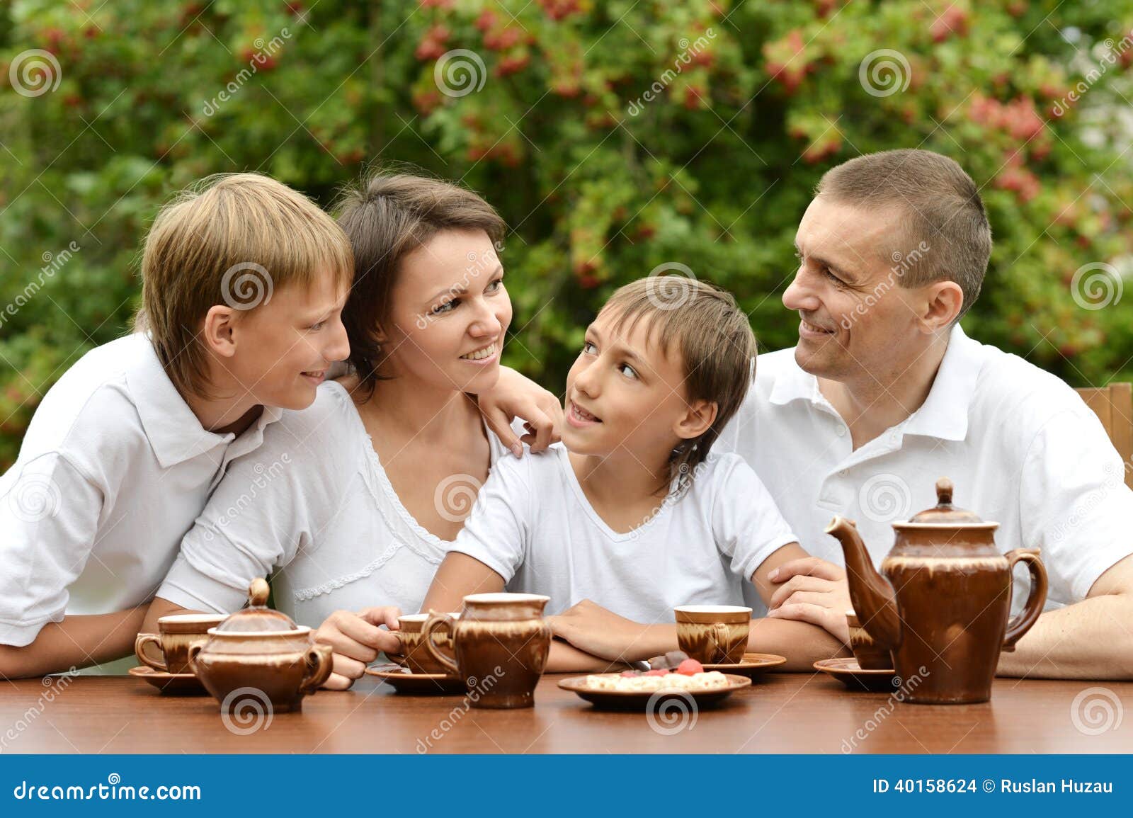 Happy family drinking tea in the garden in summer