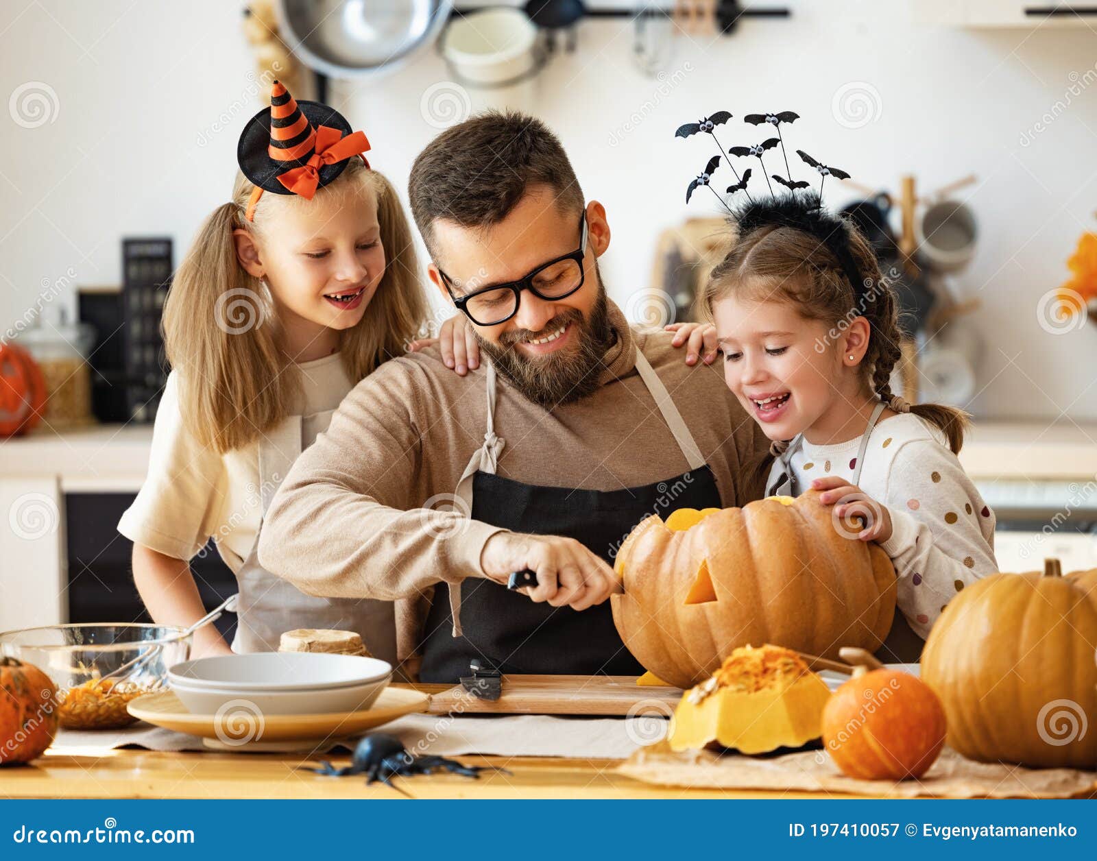 happy family   father and children prepare for halloween by carving pumpkins at home in kitchen