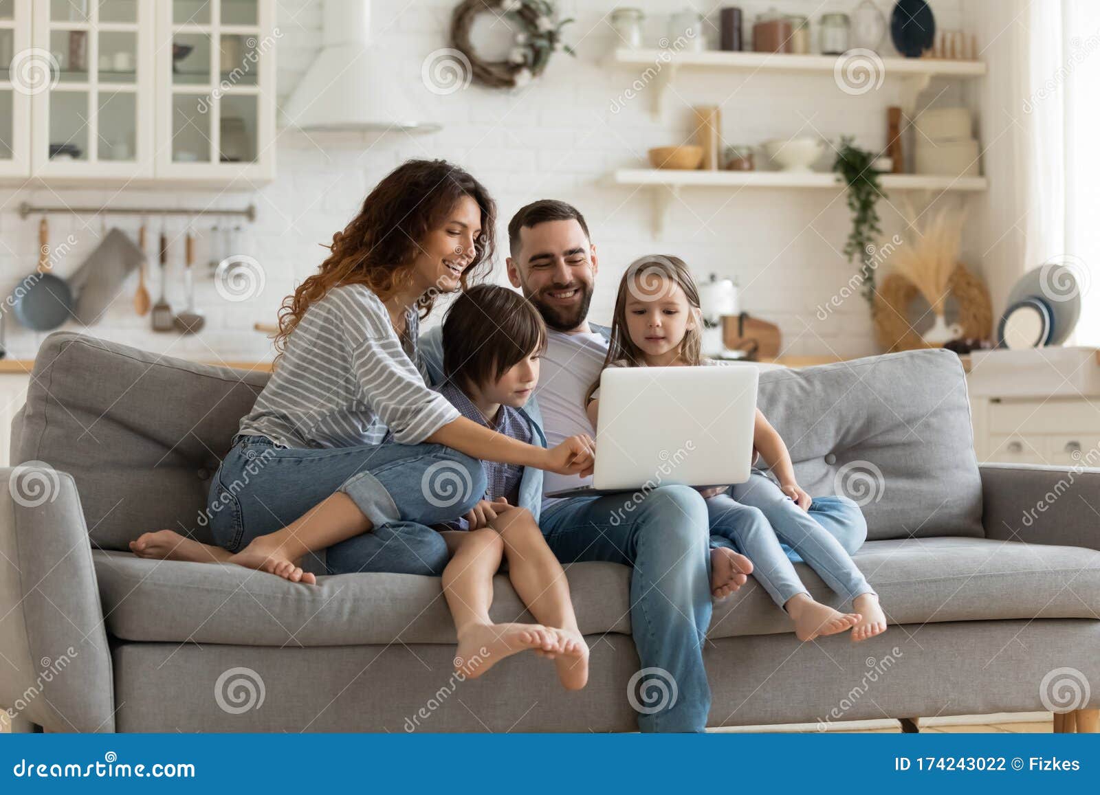 happy family with kids sit on couch using laptop