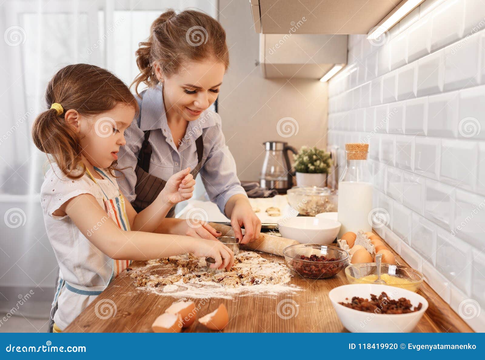 happy family in kitchen. mother and child daughter baking cookies