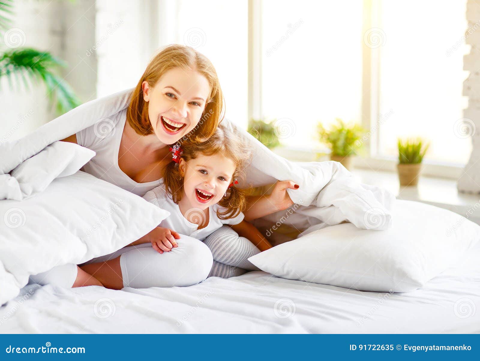 happy family mother and child daughter laugh in bed