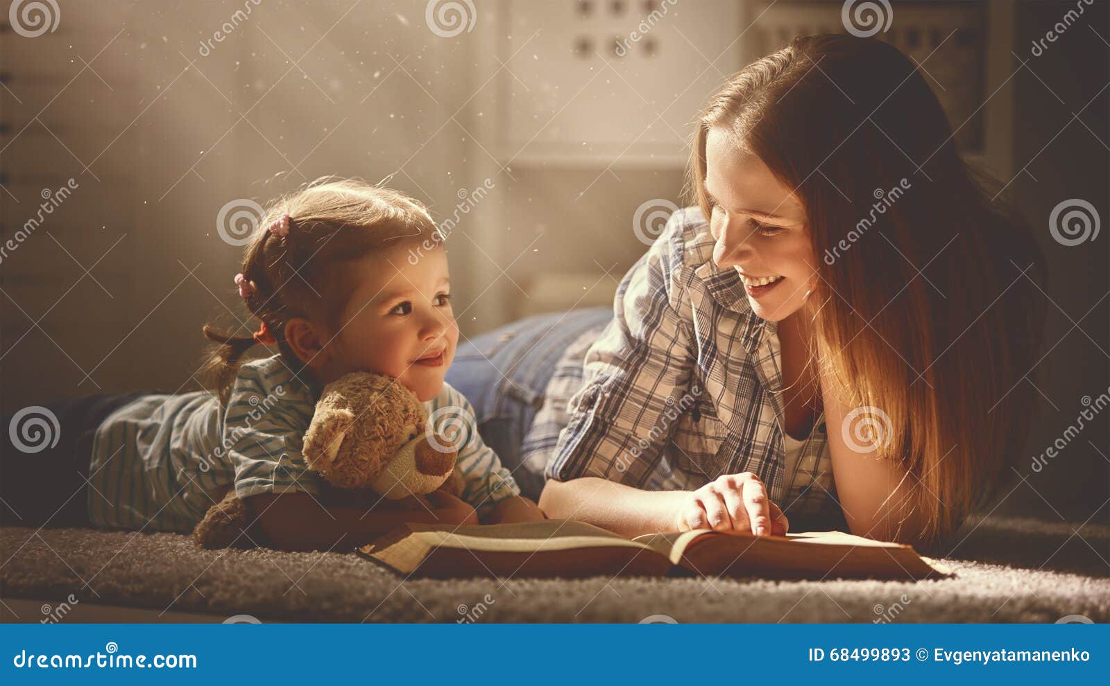 happy family mother and daughter read a book in evening