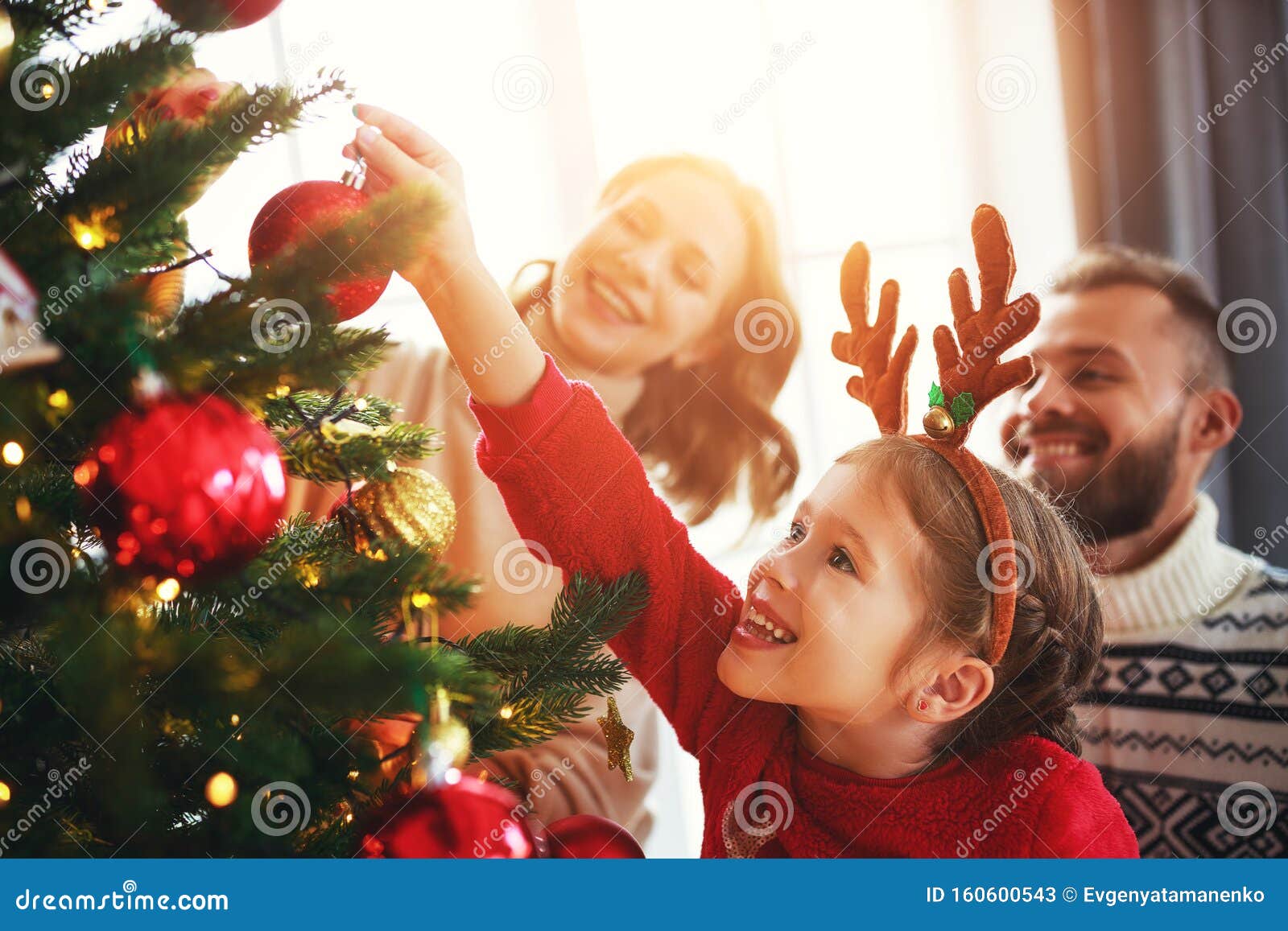 happy family mother, father and child daughter decorate christmas tree