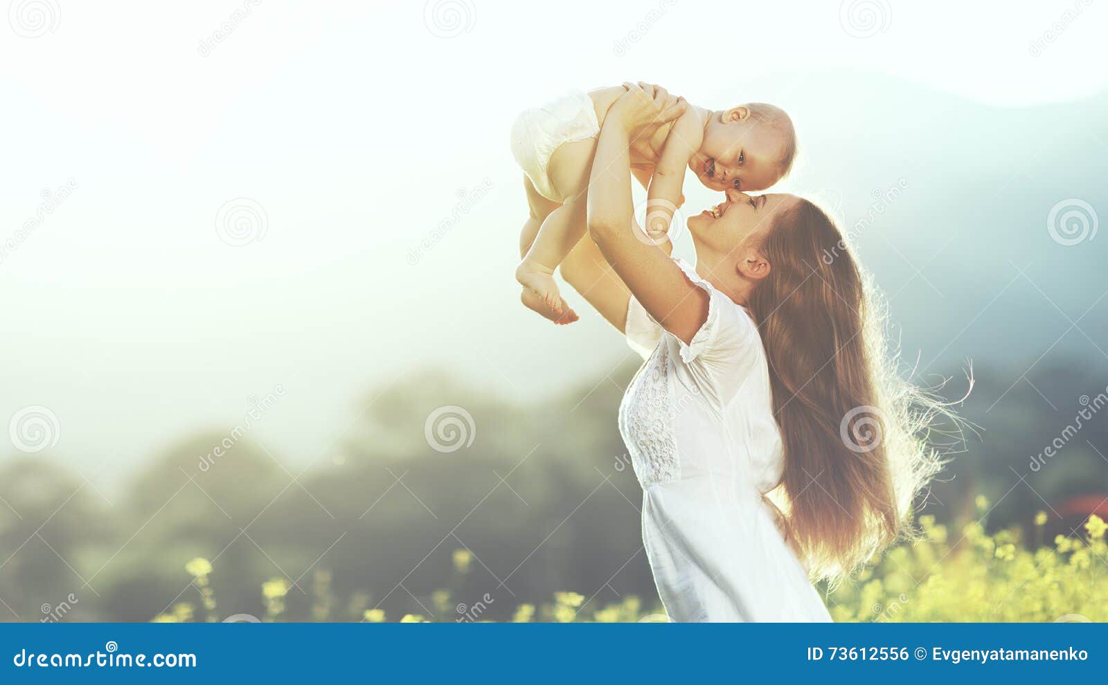 happy family outdoors. mother throws baby up, laughing and playing in summer on nature