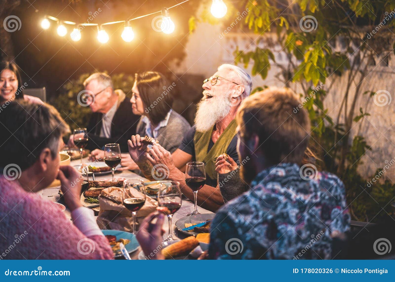 happy family people having fun at barbecue dinner - multiracial friends eating at bbq meal - food, friendship, gathering and