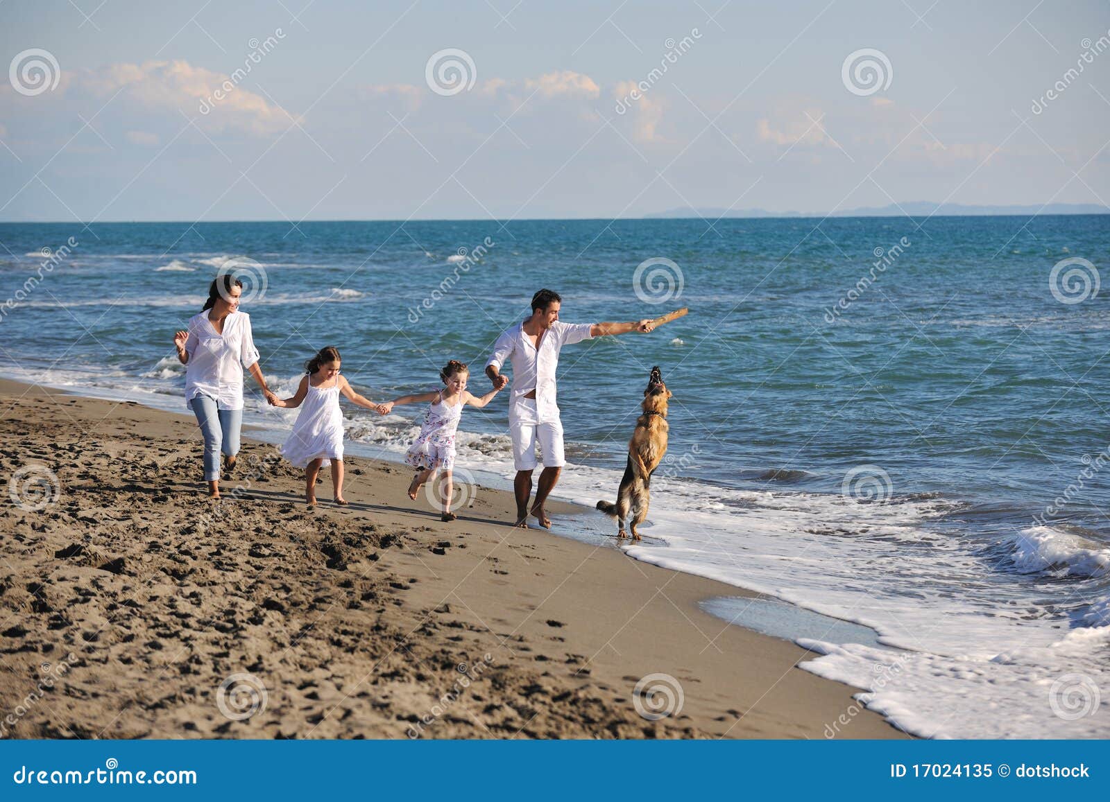 Happy family playing with dog on beach. Happy young family in white clothing have fun and play with beautiful dog at vacations on beautiful beach