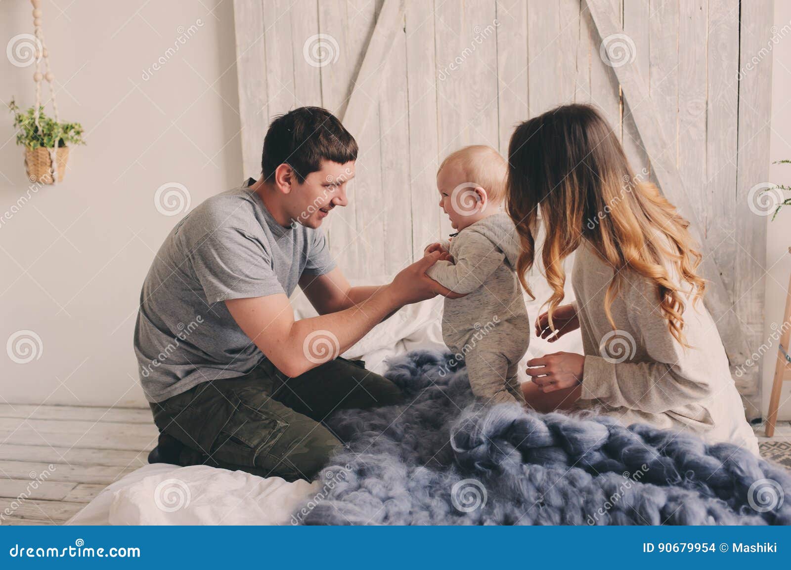 happy family playing at home on the bed. lifestyle capture of mother, father and baby