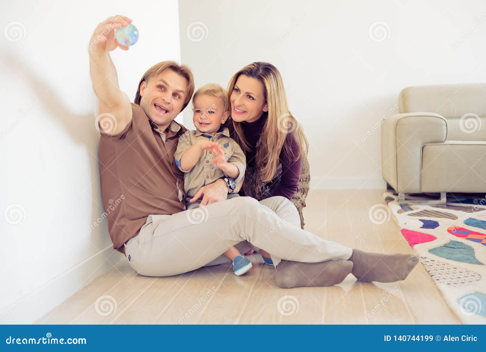 Happy Family Sitting On Floor With Their Little Baby Family