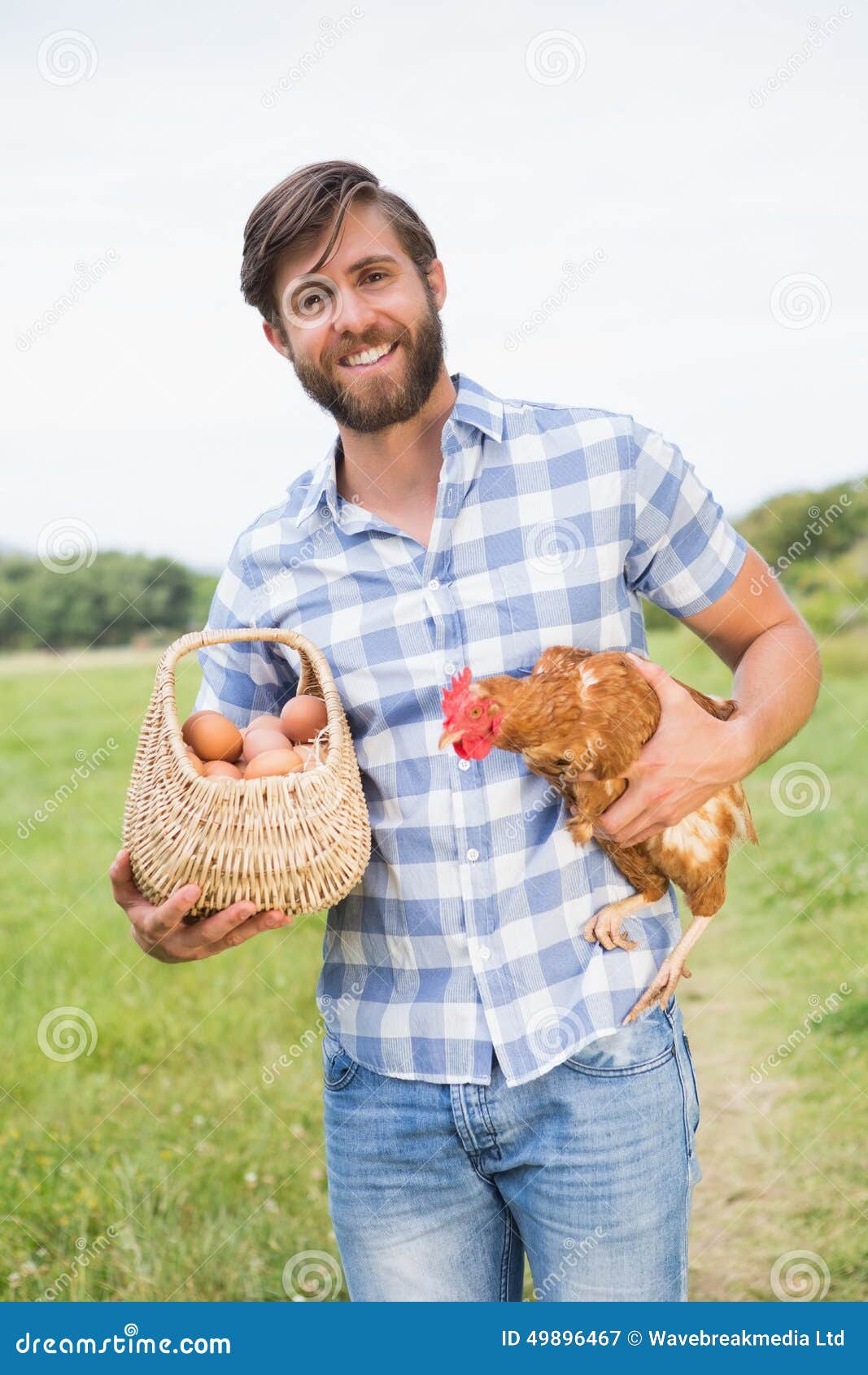 Happy farmer holding chicken and eggs on a sunny day.