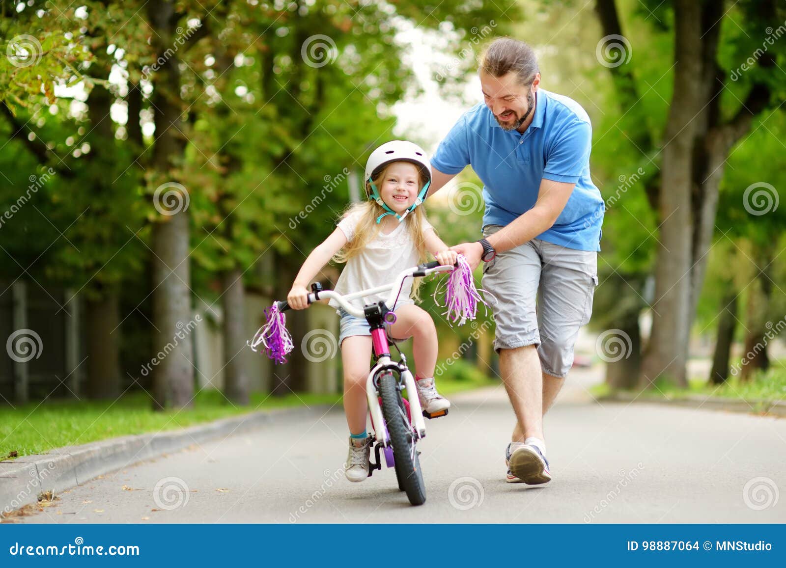 happy father teaching his little daughter to ride a bicycle. child learning to ride a bike.