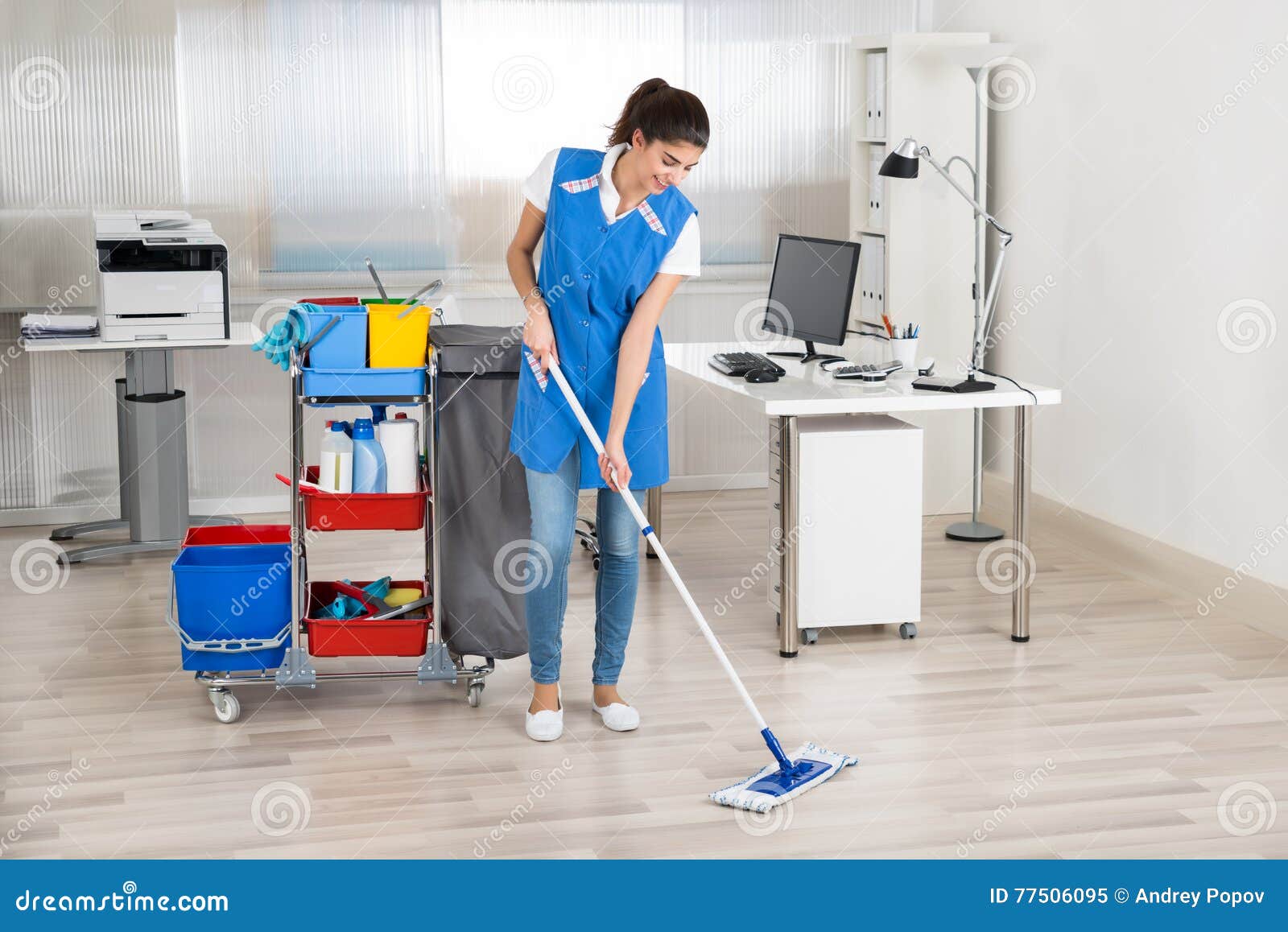 happy female janitor mopping floor in office