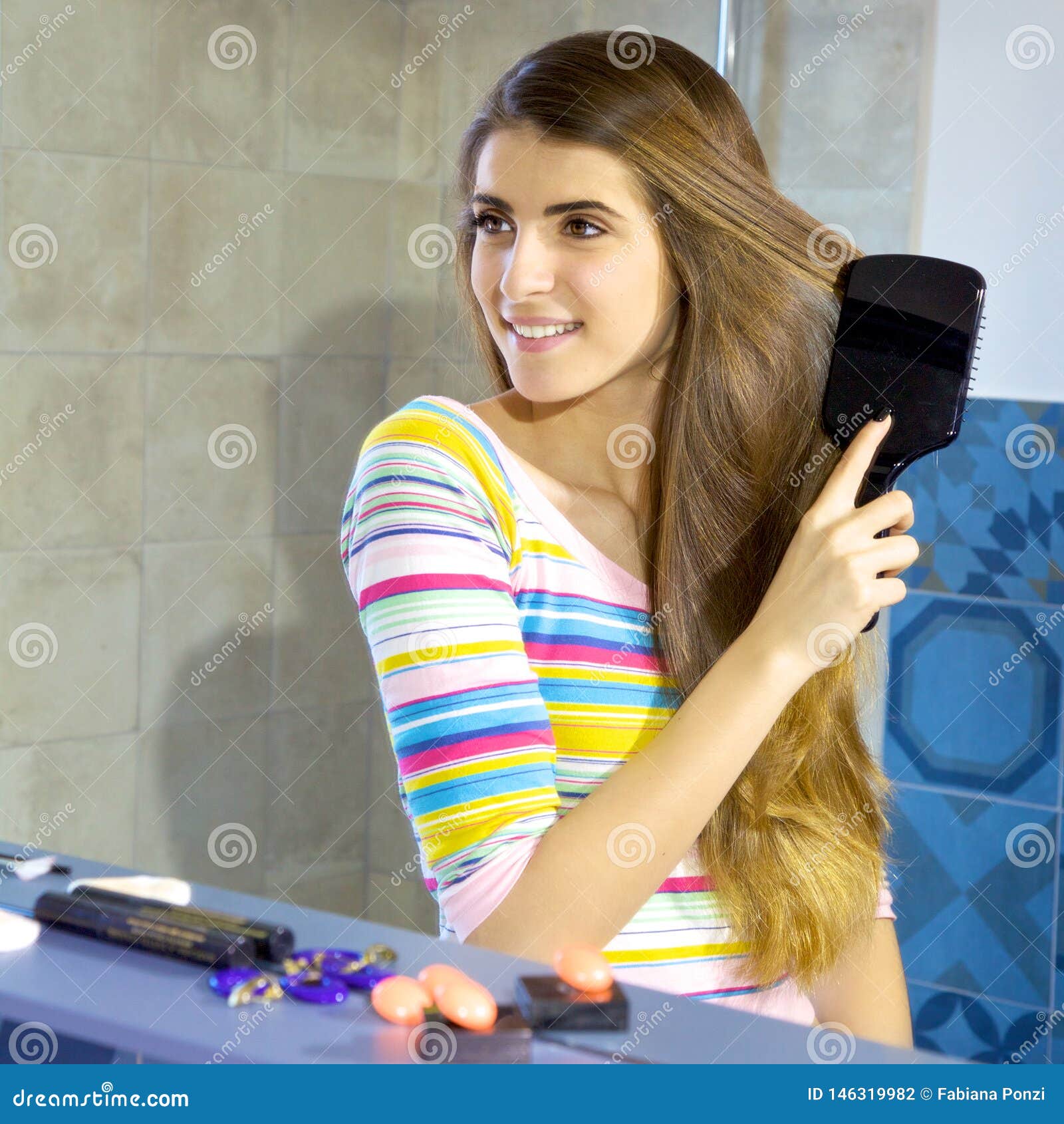 Happy Female Model In Front Of Mirror Brushing Long Blond Hair Stock 