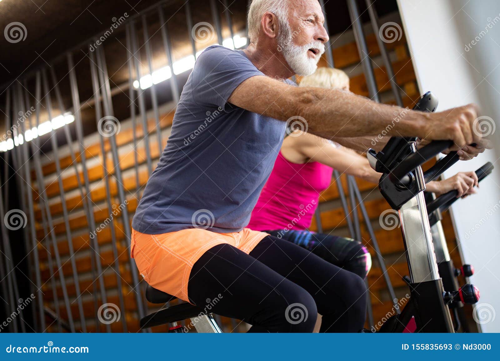 Happy Fit Mature Woman And Man Cycling On Exercise Bikes To Stay Healthy Stock Image Image Of