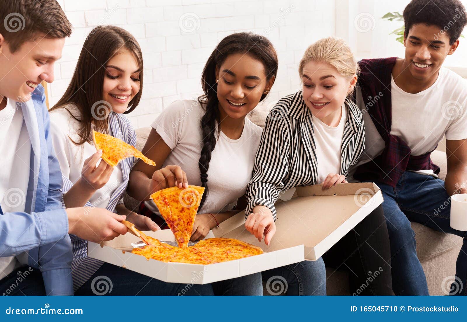 Happy african american friends eating pizza at home Stock Photo by  Prostock-studio