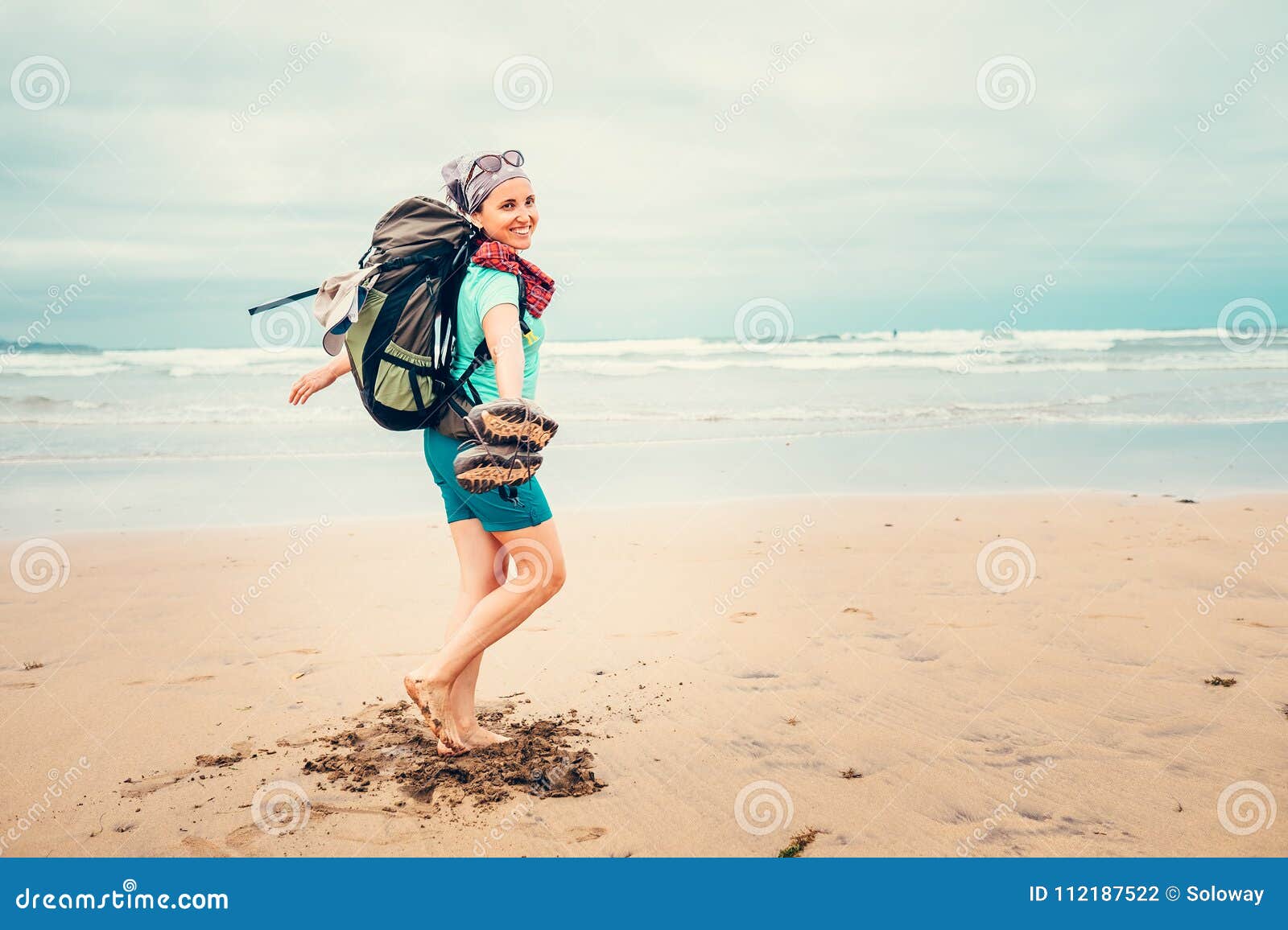 happy girl backpacker traveler runs barefoot on the sand ocean b