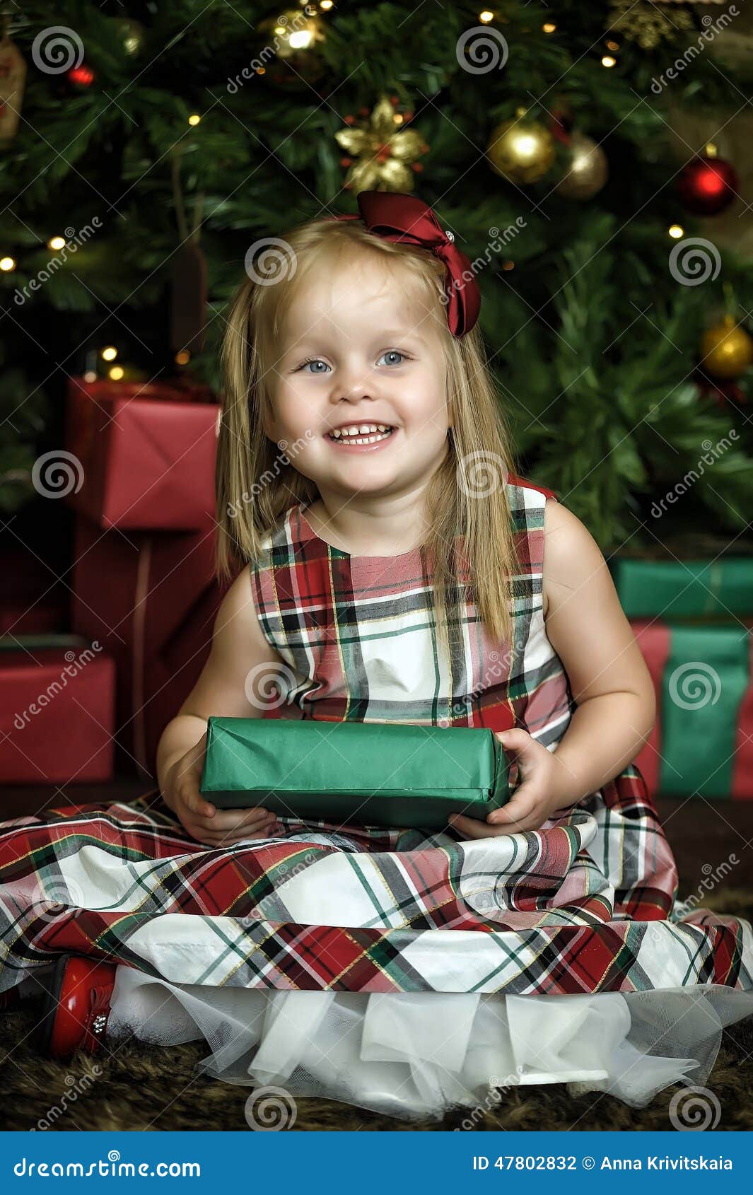 Happy girl child holding a gift in the hands of a Christmas